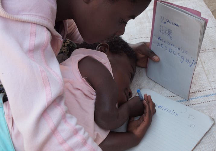 Mwiza kan niet naar school maar leert schrijven van haar zus