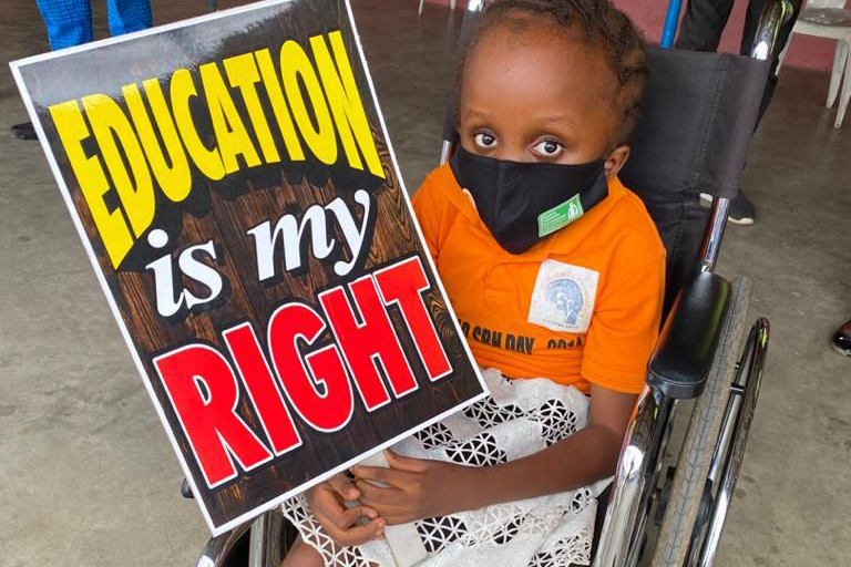 Meisje met handicap in nigeria houdt bord vast met Education is my Right