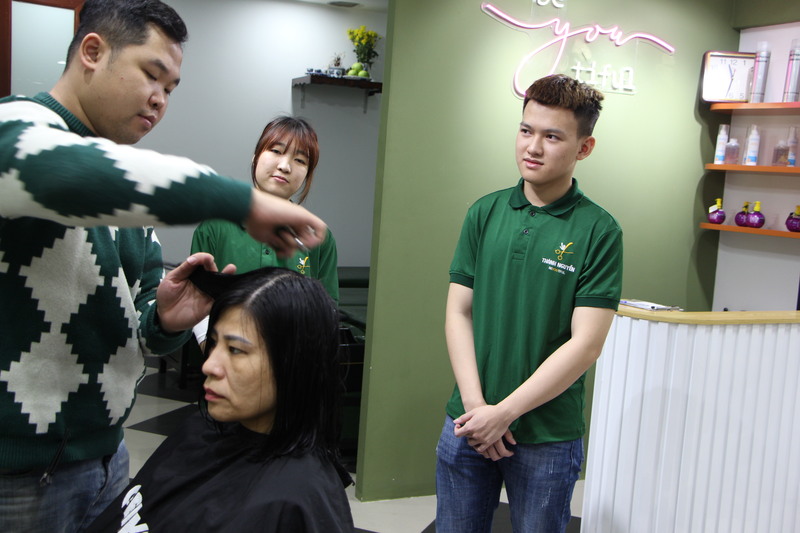 Vu en een medeleerling observeren hoe Thanh een klant knipt.