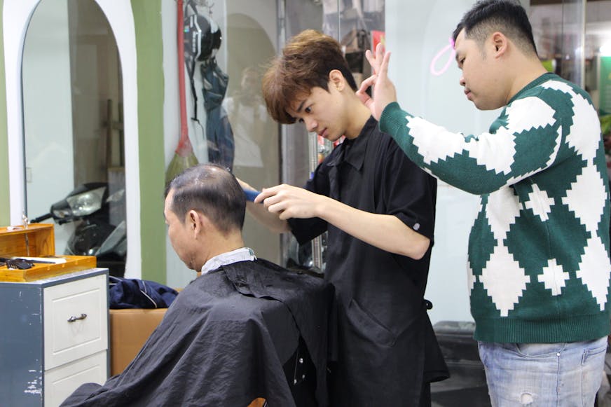 Thanh geeft instructie aan een jonge kapper die hij opgeleid heeft