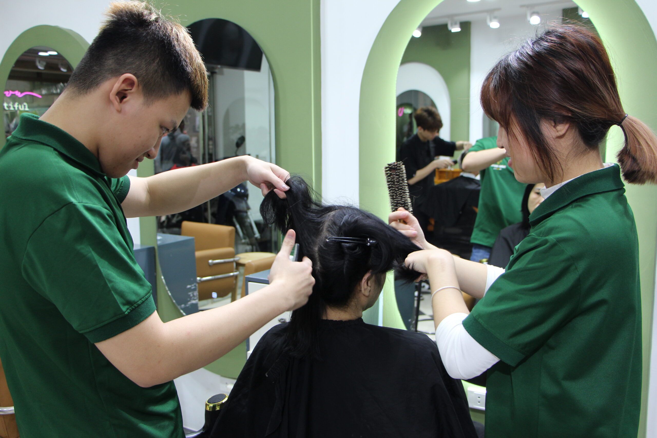 Vu en een medeleerling föhnen de haren van een klant