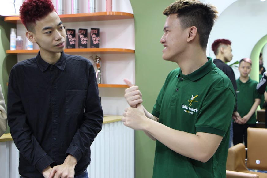 Vu en een medeleerling observeren hoe Thanh een klant knipt